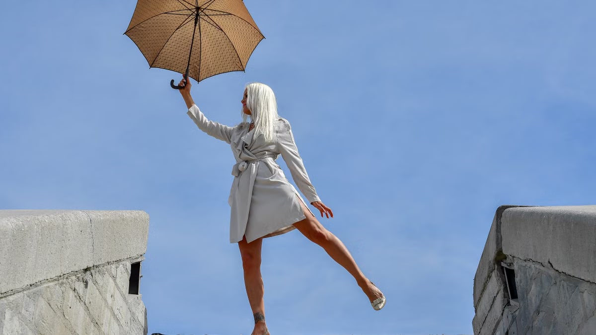 A stylish woman with an umbrella gracefully poses on stairs in Tallinn, Estonia.